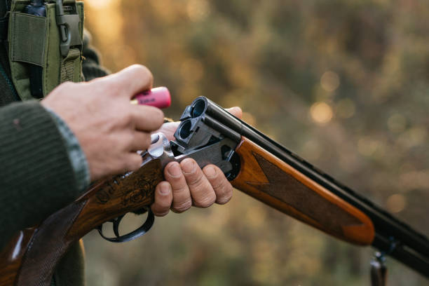 Hunter man loading his gun while hunting outdoors. Hunting season concept.